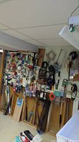 Wide view of basement wall with pegboards holding various small tools, hardware, tapes, cords, and hand tools.