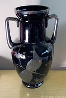 Front view of tall amethyst glass vase with dual handles and silver overlay peacock and flowers design, showing no damage.