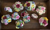 Top view of all 10 bone china floral figurines arranged in a tray showing colors, size, and condition overall.