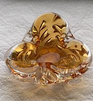 Top view of amber glass decorative sculpture showing curved form and amber color.