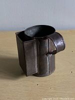 Front and handle side view of the rectangular tin shaving mug with cylindrical handle showing wear and patina.