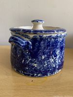 Side view of a blue speckled ceramic pot with lid and small handles