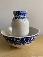 Ceramic bowl and vase displayed together. Blue speckled decoration on white ceramic.