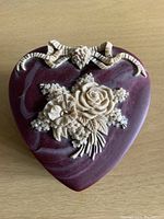 Top view of heart-shaped Incolay stone box showing carved floral design in ivory color on lid.