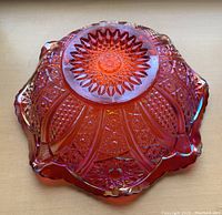 Overhead image showing the intricate starburst and geometric pattern of the underside of the bowl with vibrant sunset red iridescence.
