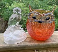 Photo of a vintage orange honeycomb fox vase and a clear glass owl figurine on wooden surface outdoors