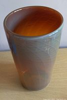Angled top view of the iridescent vase showing its tapered opening and amber interior.