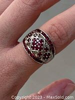 Ring worn on finger showing garnet stones and lattice silver design