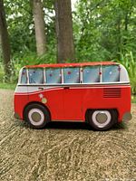 Photo showing side view of red Volkswagen camper van tin with festive window decorations and wheels.