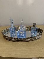 Photo showing all four perfume bottles placed on the oval mirrored tray from the front angle.