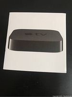 Front view of the white Apple TV box displaying the image of the black device