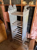 Folded Featherlite aluminum ladder leaning in a garage, showing rungs and construction.