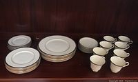 Full set arranged on shelf showing stacks of plates and row of cups