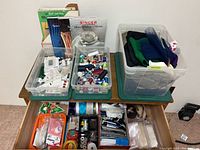 Overview of three plastic totes on a dresser and one open drawer containing sewing supplies and notions.