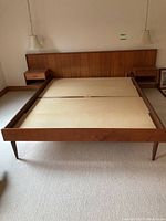 Frontal view of teak platform bed frame with headboard and integrated nightstands