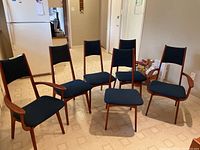 Group shot of all six teak dining chairs arranged in a room