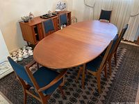 Oval dining table with leaf installed and six chairs arranged around
