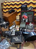 Front view of all items on patterned blanket including cameras, lenses, box and accessories