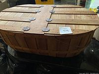 Full view of the wooden basket showing the top with metal hinges and side handles.