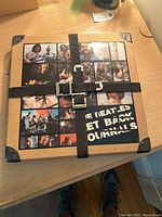 Front of closed cardboard box with photo collage and black straps