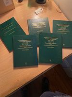 Five green coin albums with gold embossed titles for presidential dollars, fifty state quarters (two albums covering 1999-2008 and 2009), and America the Beautiful quarters from 2010 to 2021 arranged on a wooden table.