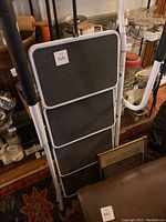 Folded view of the 4-step collapsible step stool showing the black textured steps and metal frame with handles.