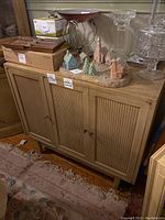 View of the three door dining cabinet with decorative items on top including miniature ceramic houses and glassware