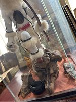 Monkey sculpture inside hexagonal glass case on driftwood and sand base