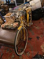 Front angled view of the gold Raleigh Sports bicycle highlighting the front wheel, headlight, handlebars, and frame.