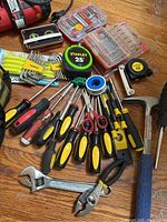 Overview of assorted hand tools including screwdrivers, wrenches, pliers, tape measure, scissors, Teflon tape, magnetic wristband