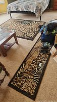 View of animal print area rug beside bed and matching runner rug with shoes on it