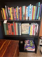 Full view of two shelves filled with books and a third shelf with two board game boxes Q-bitz and Qwirkle.