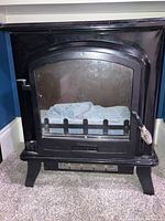 Front view of black Decor Flame electric space heater showing glass window and metal handle on right side