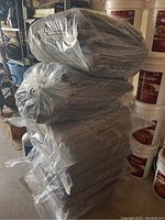 Stack of six plastic bags filled with folded gray moving pads/blankets, showing the quantity and packaging.