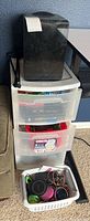Photo of black compact mini fridge sitting on top of white plastic three-drawer storage unit holding clear drawers with craft items inside