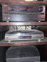 Image showing front face of Onkyo TX-NR646 AV receiver and Technics CD player stacked in dark wooden shelving.