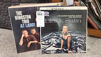 Two vintage vinyl records with original covers: The Kingston Trio At Large with two band members pictured, and George Shearing Quintet Black Satin with a woman in a black satin dress on the cover.