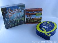 Photo showing the three board games: Bunny Kingdom, TransAmerica, and Quiddler Deluxe tin.