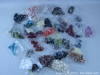 Photo showing multiple small plastic bags filled with beads of various colors and materials spread out on a surface.