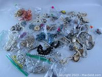 Image showing assortment of vintage necklaces, earrings, and brooches in plastic bags on a flat surface.