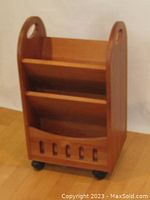 Front view showing two angled shelves, cut-out handle sides, and caster wheels