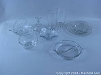 Overview of the entire Candlewick glassware set showing handled basket, divided relish dish, water glasses, plates, bowl, and candleholders all with signature beaded edges.