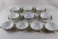 Front view of all cream soup bowls and saucers arranged together showing patterns and condition.