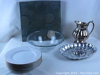 Photo showing set of 6 white plates with gold rims, large clear glass bowl, metal serving trays, and stainless steel pitcher.