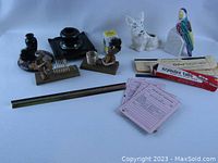Photo showing vintage desk items including ceramic inkwells on wooden bases, two ceramic figurine planters/pencil holders (a dog and a parrot), two wooden troll letter holders, a brass architect ruler, vintage pink message pads, and a box of Ezyindex tabs.