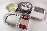 Full set of baking pans including Wilton round cake pan, Nordic Ware brownie pan, loaf pans, Chefmate springform pans, and fluted tart pan.