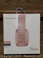 Front view of the ALPHA Pulse X headphones box showing pink headphones illustration and branding.