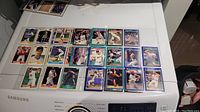Photo showing over 30 baseball cards from 1989 to 1991 placed in plastic protective pages, displayed on a white surface with some visible card details such as player images and team colors.