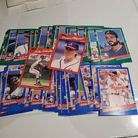 Photo shows a spread of over 40 1991 Donruss Atlanta Braves baseball cards laid out on a flat surface. Cards feature multiple players with colorful blue and green borders, in near mint condition.