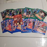 Photo shows an array of over 50 1991 DonRuss Chicago Reds baseball cards spread out on a white surface, displaying green and blue backs with player photos and team logos visible.